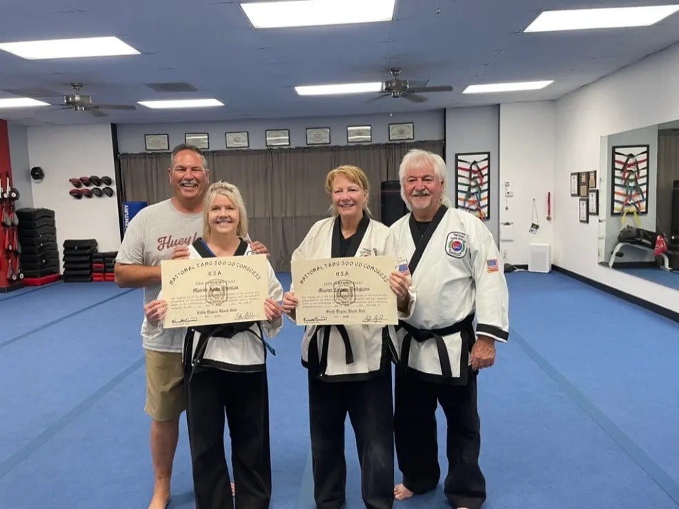 Martial arts students displaying achievement certificates