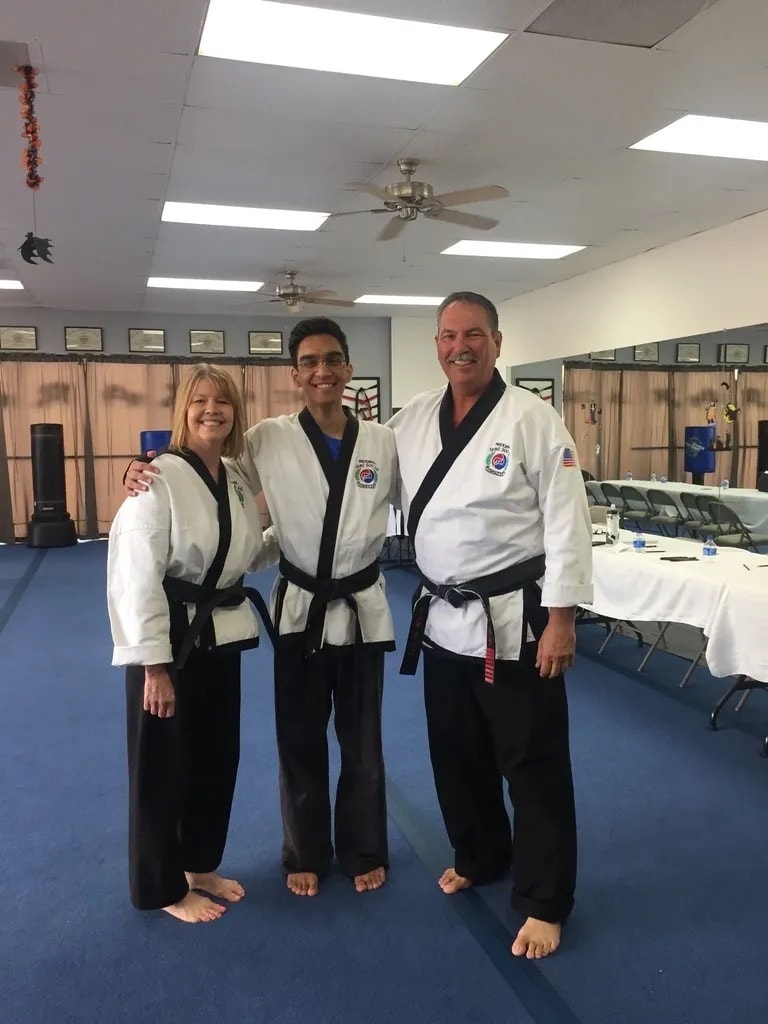 Three martial artists posing in dojo