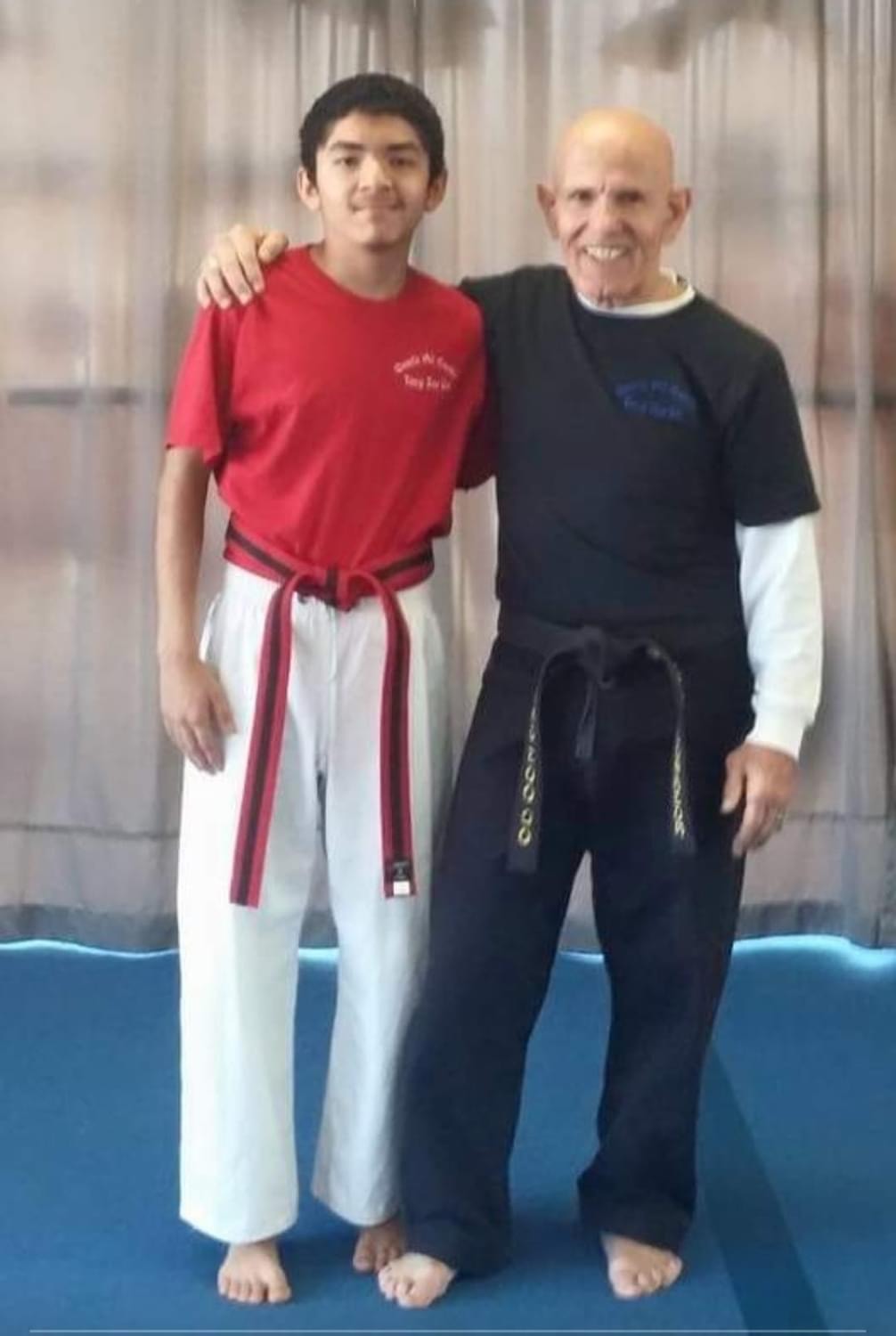 Young student and instructor posing together in dojo