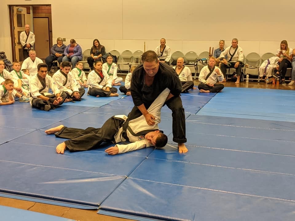 Instructor demonstrating ground technique to audience at martial arts event