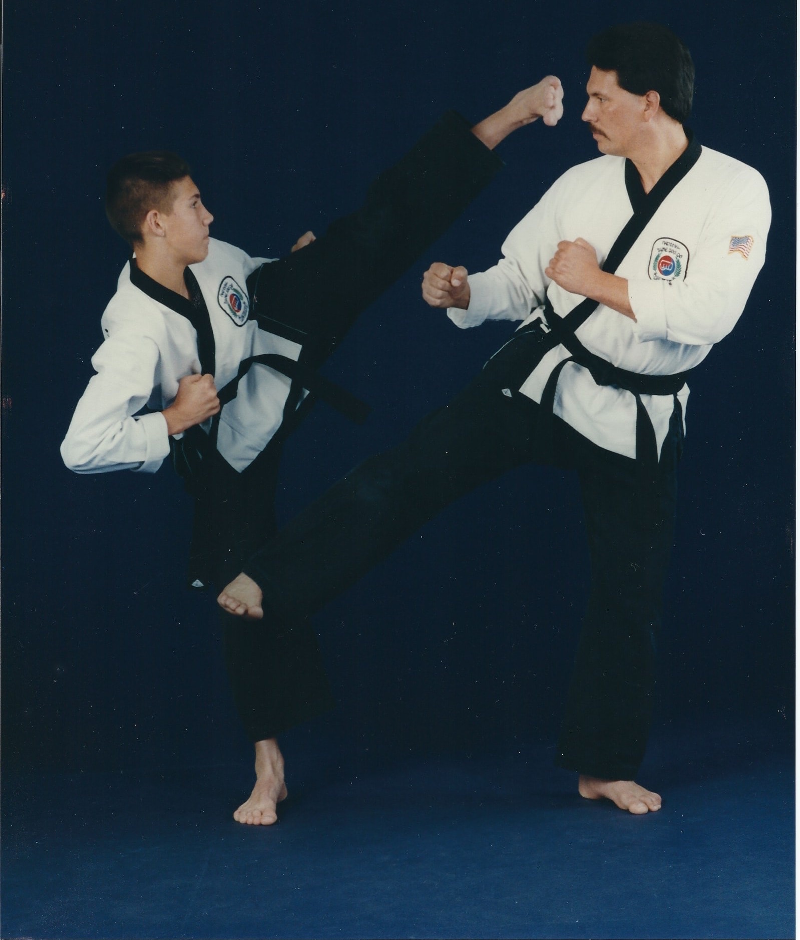 Two martial artists sparring with high kick on blue background